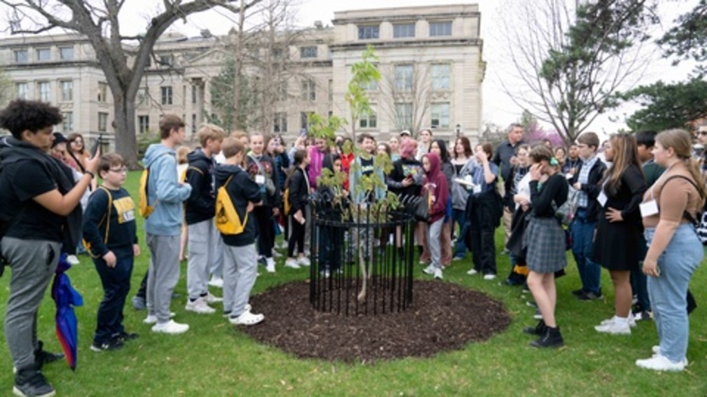 Students surrounding the Anne Frank tree sapling on the University of Iowa Pentacrest